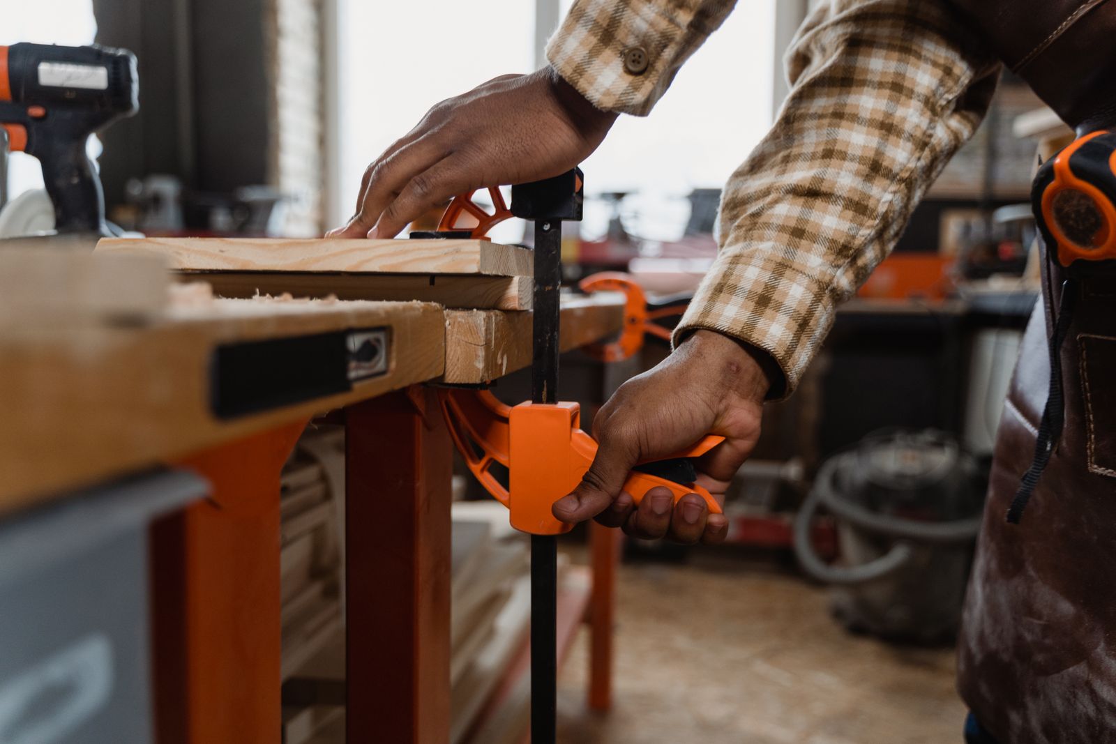 A craftsperson clamping wood at a workbench in a workshop.